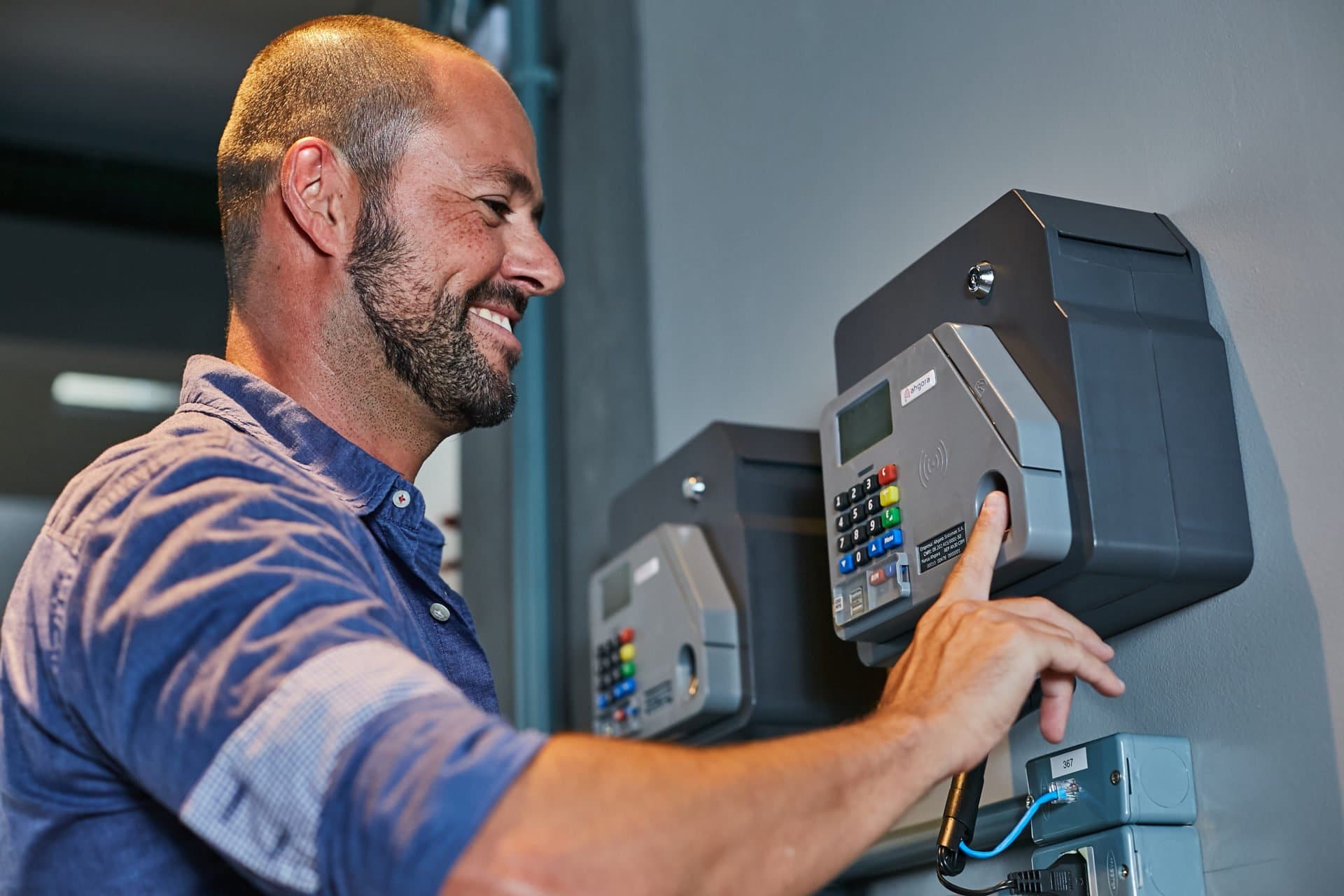 Blog ahgora - Homem sorrindo batendo ponto eletrônico da Ahgora